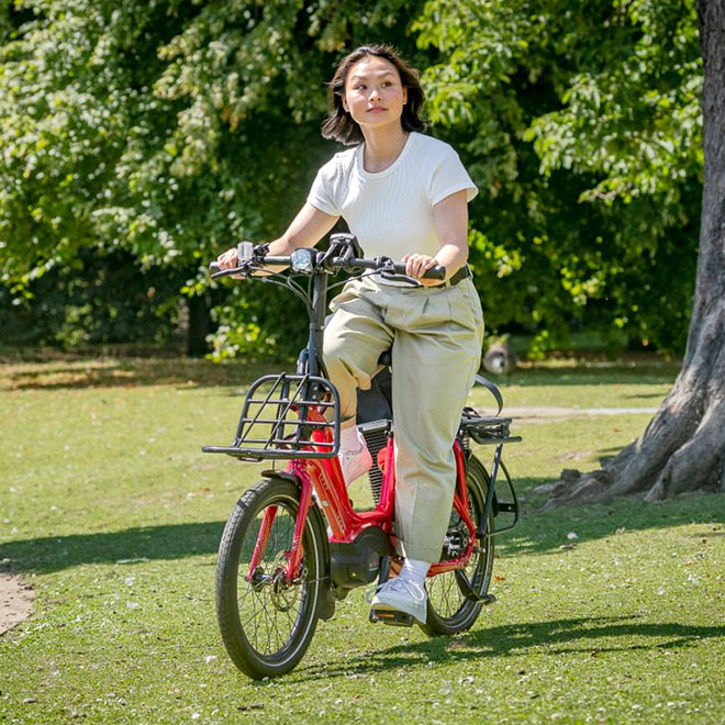 A woman riding the Tern NBD, an ultra low-step ebike with a Hauler Rack installed at the front.