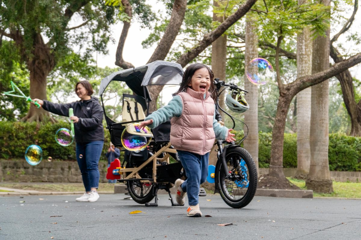 Mom and child has fun in the park, with Tern GSD cargo bike in the background