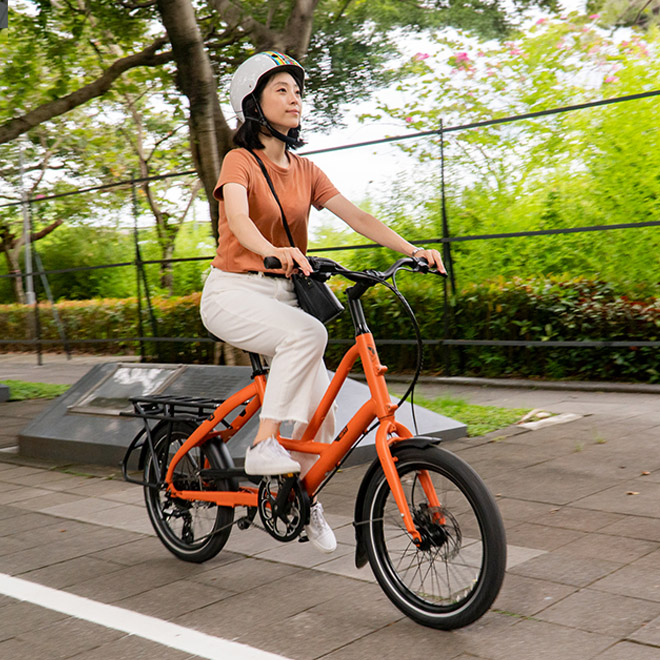 A woman wearing a helmet rides an Short Haul cargo bike. 