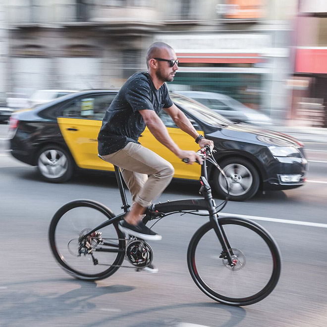 A man is riding Eclipse folding bike on the street.