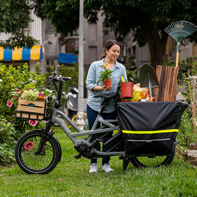 A woman is putting potted plants into a Storm Box on a GSD cargo bike.
