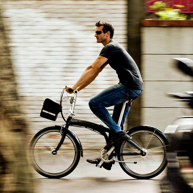 A man rides an Eclipse folding bike with a front bag.