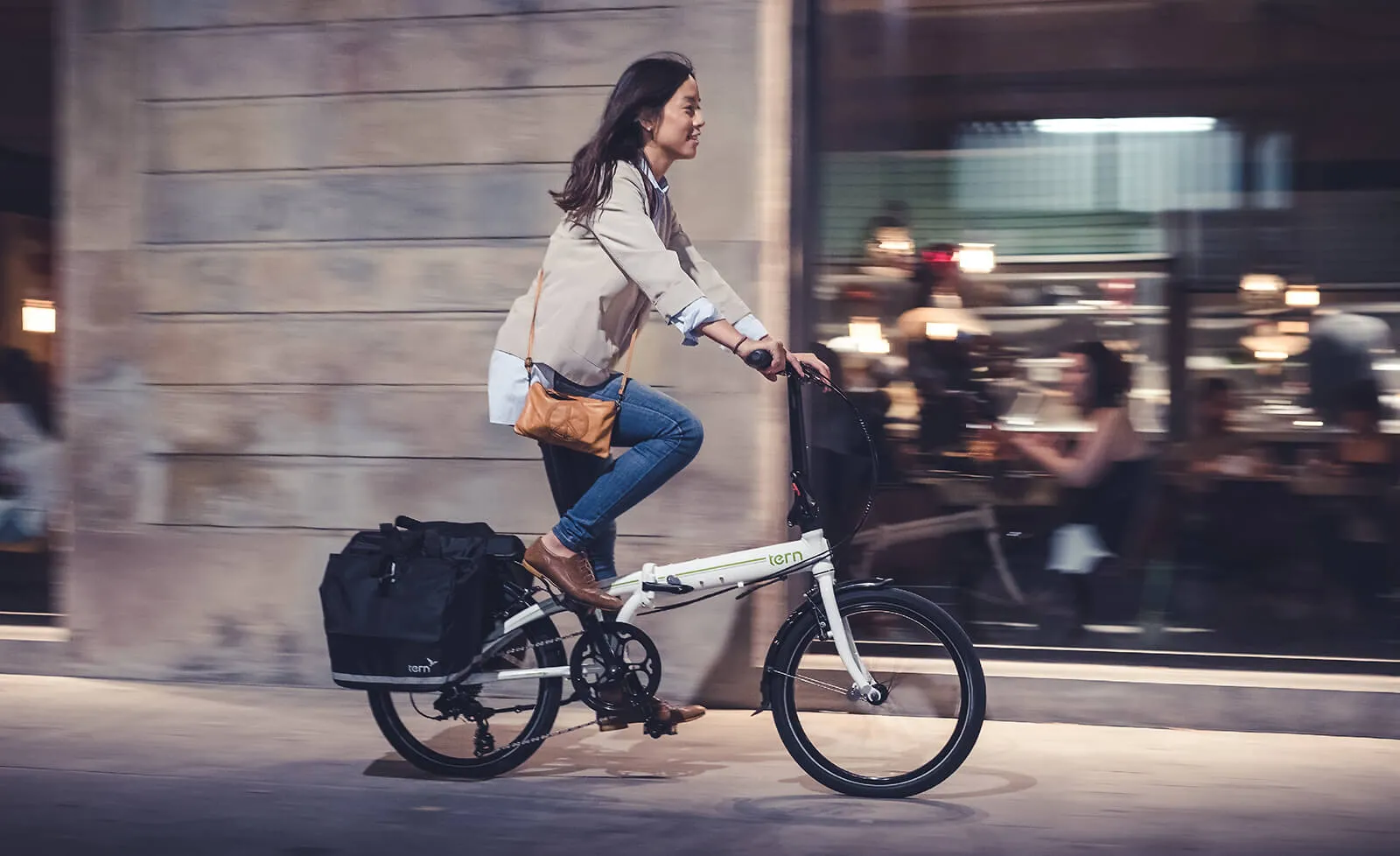 A young lady riding a folding bike passing by a modern restaurant