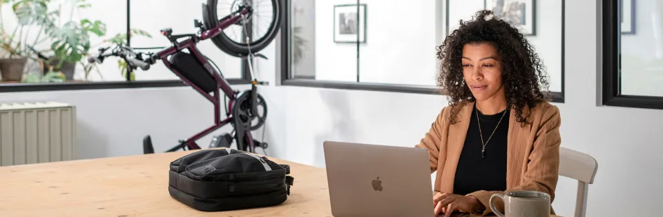 A bicycle parks vertically in the office scene behind the woman working at her computer