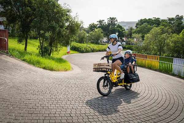 Woman riding the Tern GSD cargo bike for family, carrying a child in a Clubhouse on the rear rack.