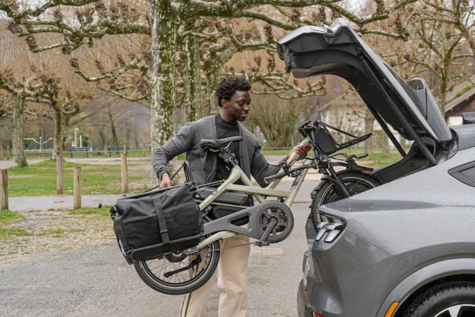 A man putting his Tern HSD e-cargo bike in FlatFold mode into the trunk of his car.