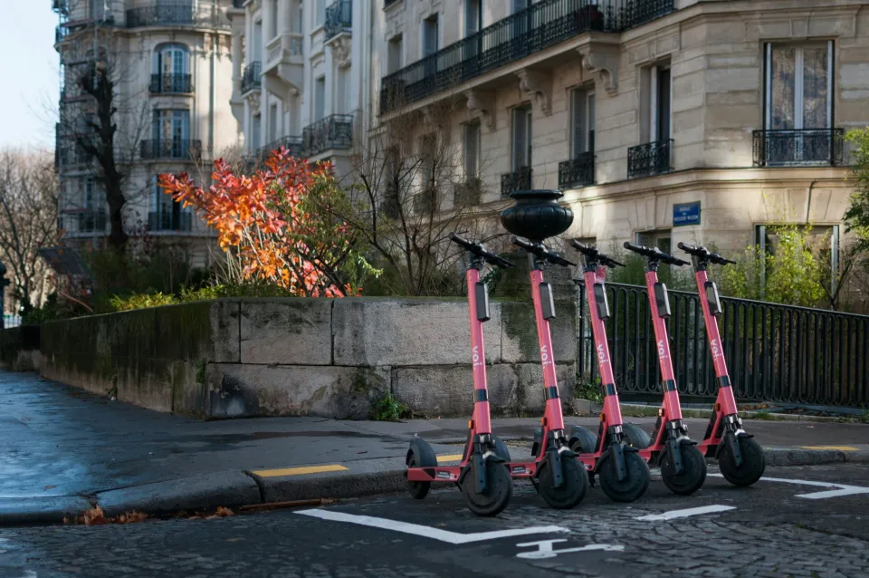 A row of rental electric scooters on the side of the road in Paris.