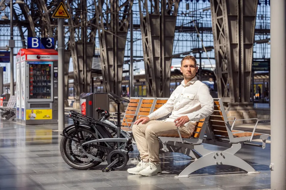 Commuter sitting on a train platform with the Tern Vektron Gen 4 folding ebike