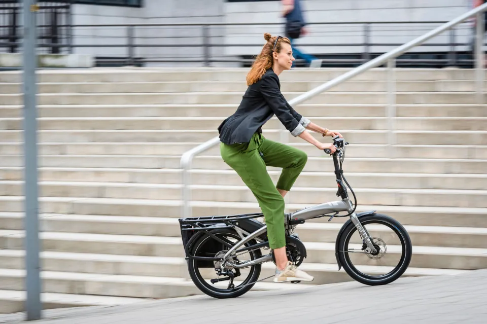 A woman riding a compact Tern Vektron folding e-bike.