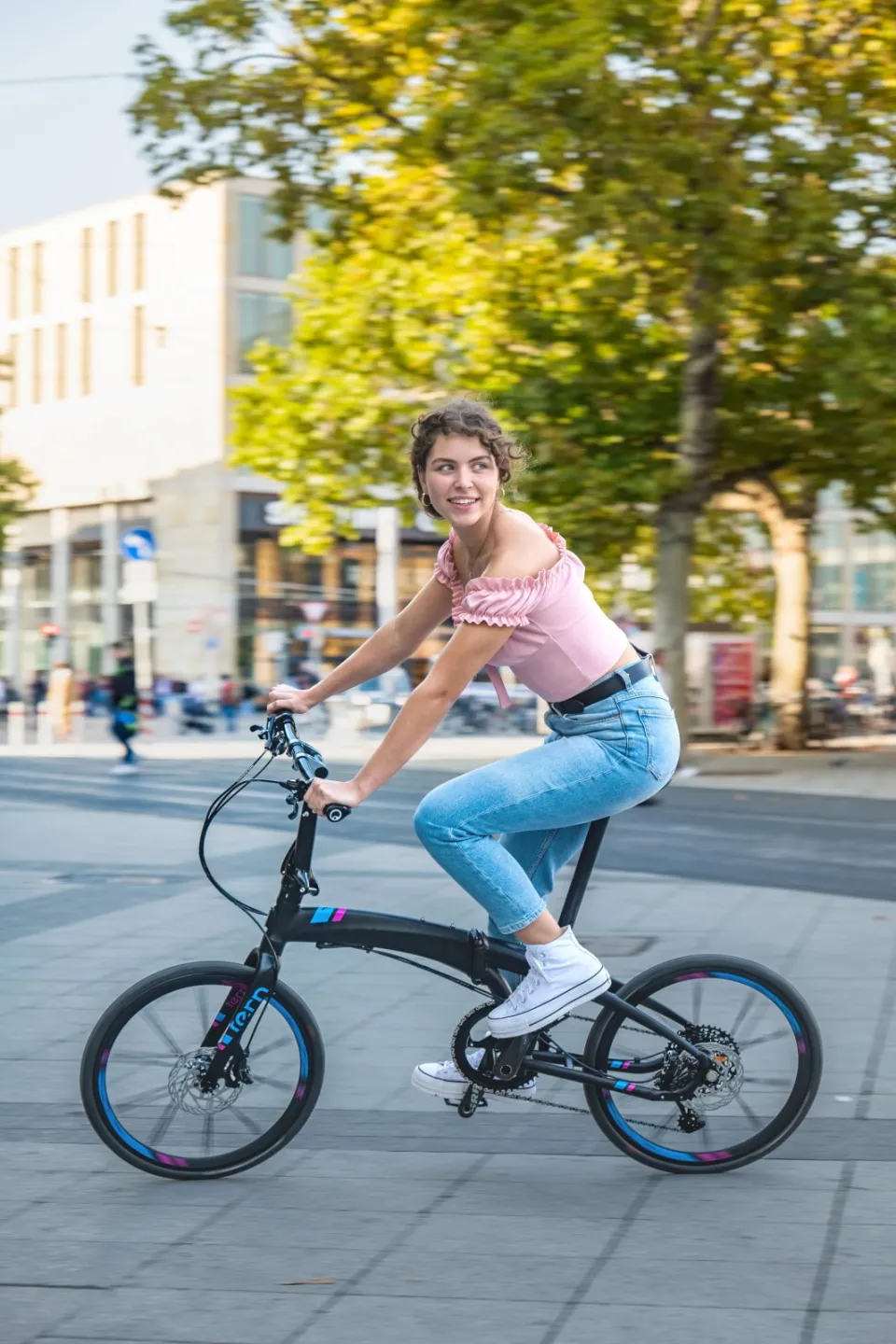 A young woman riding Verge X11, a high performance folding bike.