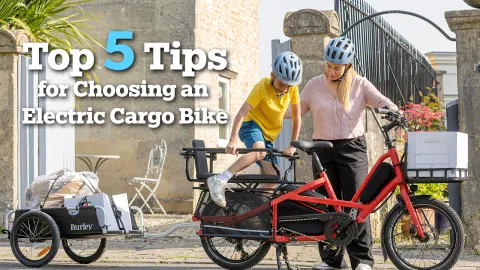 Article banner image depicting a woman and her child getting on the Tern Quick Haul Long electric cargo bike with a Burley trailer attached.