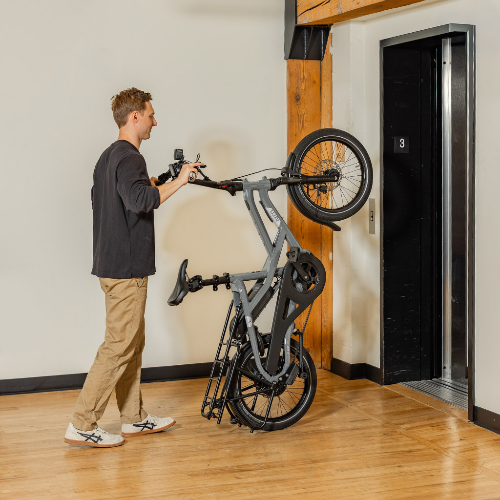 Een man rolt een Tern HSD e-cargobike verticaal in de lift.