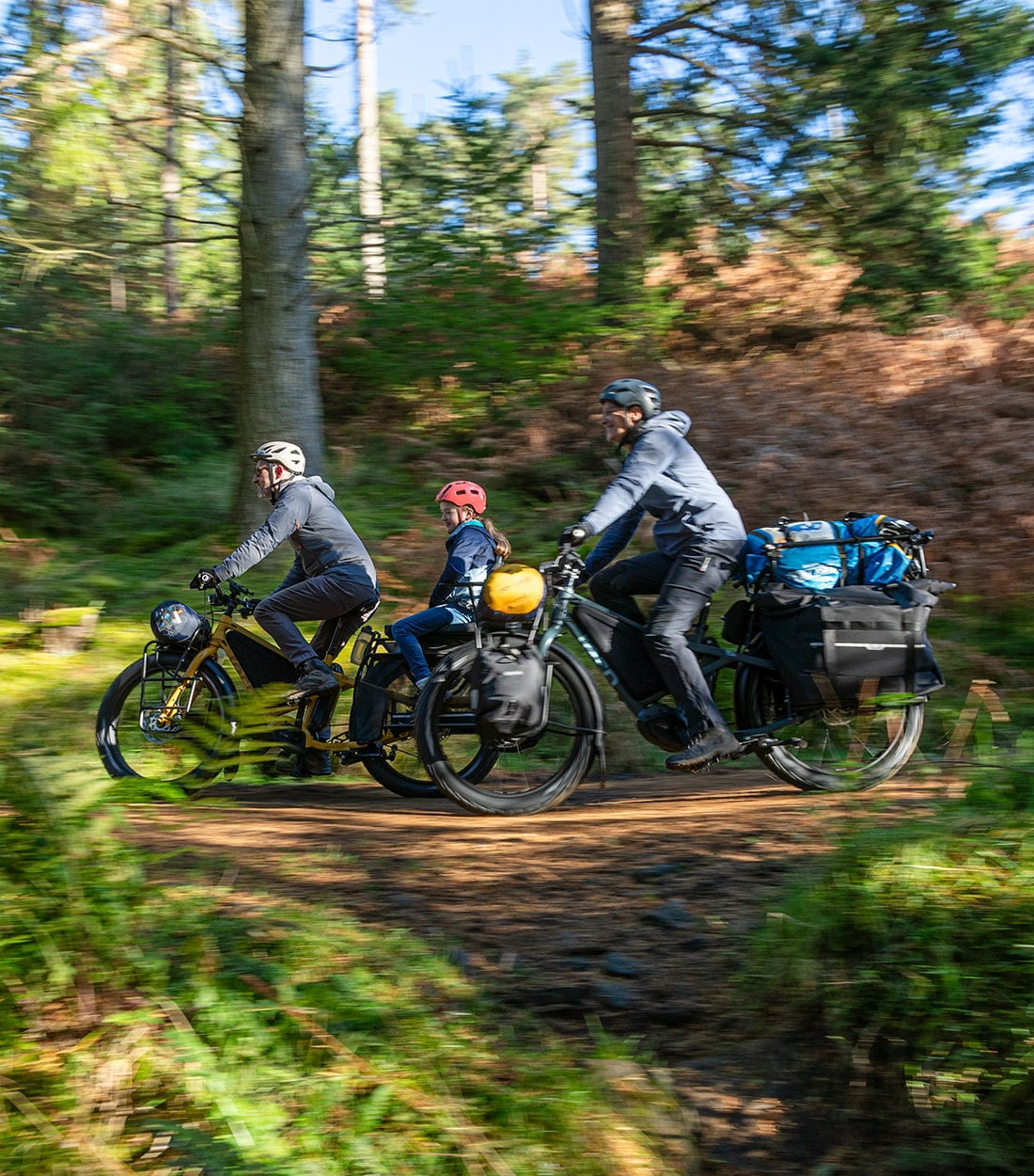 Two bikes with one carries loads of stuff on the rear rack and another one with a girl on the back seat