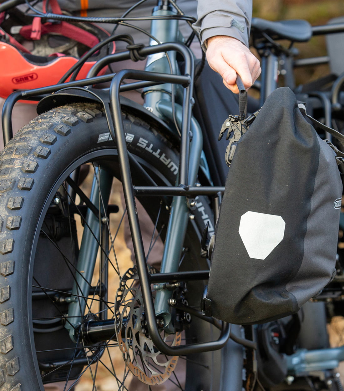 The rider loading pannier on the front rack on the side of a bike