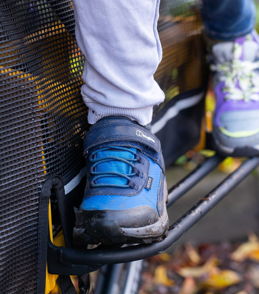 Two children's feet standing on the stow deck of a bike